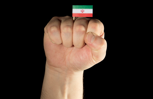 Man hand fist with Iranian flag isolated on black background
