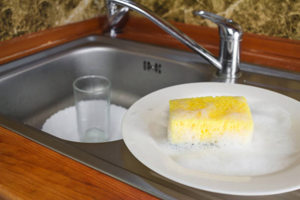 istock Sponge with foam for washing dishes on white plate at the kitchen. 645785048