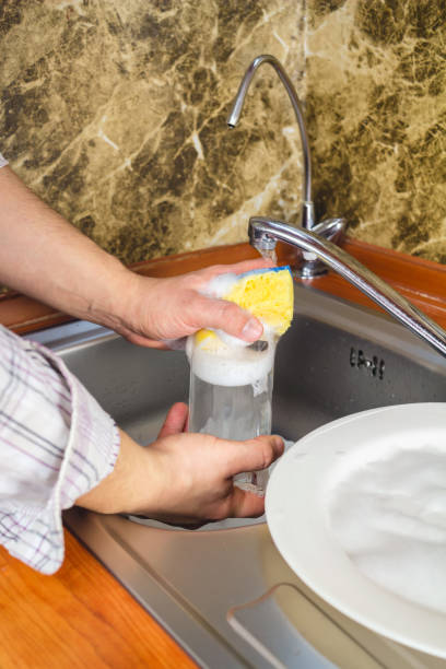 istock Man hands, washing a sponge with foam the dishes at the kitchen. 645785132