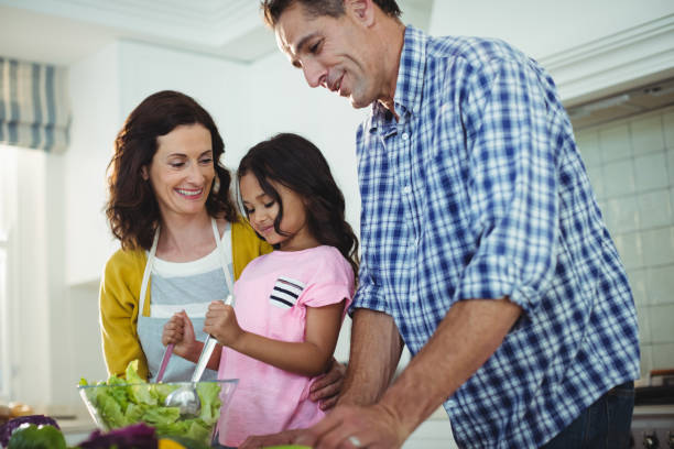 istock Parents and daughter preparing salad in kitchen 645791716
