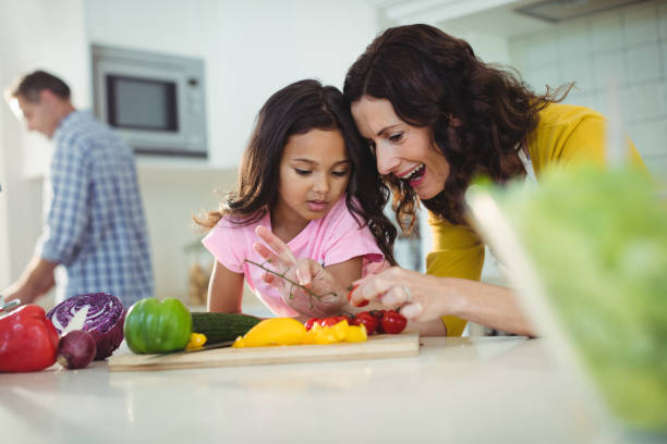 istock Mother and daughter preparing salad in kitchen 645792016