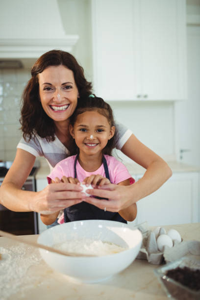 istock Mother and daughter breaking egg in bowl while preparing cookie 645794502