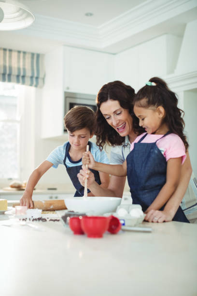 istock Mother and kids mixing the dough while preparing cookies 645794756