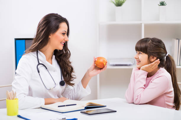 Female doctor showing apple to a child stock photo