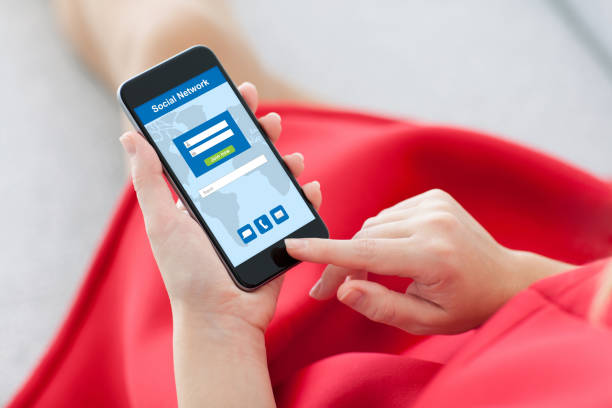 woman in a red dress holding a phone with social network on the screen