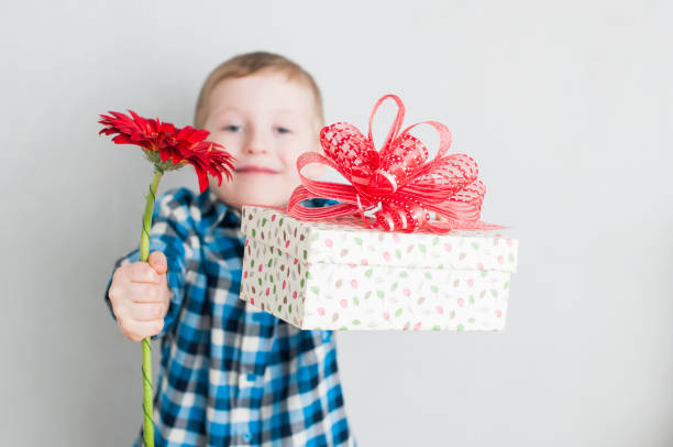 little boy with red flower and gift box stock photo