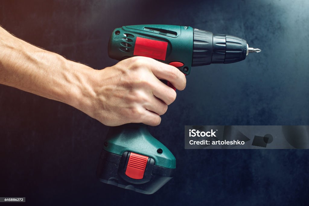 male hand holding a screwdriver, for screwing screws male hand holding a screwdriver, for screwing screws on black background Drill Stock Photo