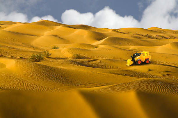 istock Desert - colourful patterns with yellow toy bulldozer & sky is visible behind 645891648