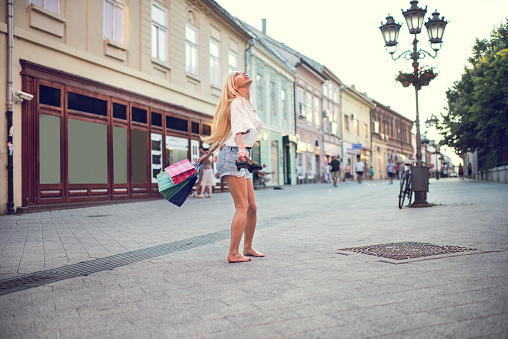 Young woman feeling free while spinning on the street with shopping bags.