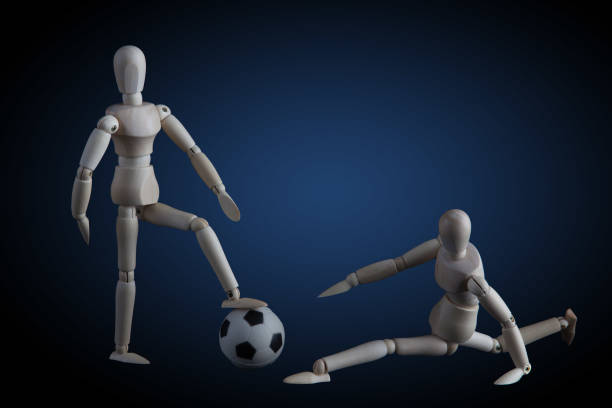 istock Two wooden figurines playing soccer concept on dark background with blue spotlight 645941432