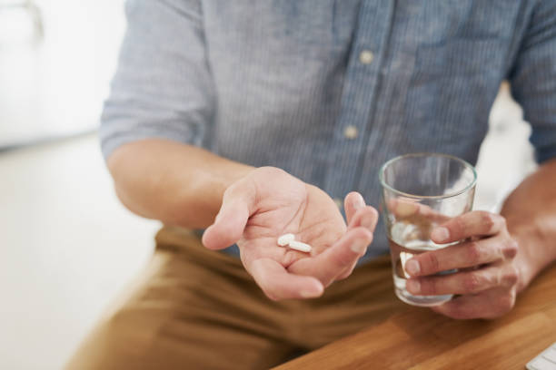 Taking his prescribed treatment Closeup shot of an unrecognisable man holding a glass of water and medication in his hands antibiotic stock pictures, royalty-free photos & images
