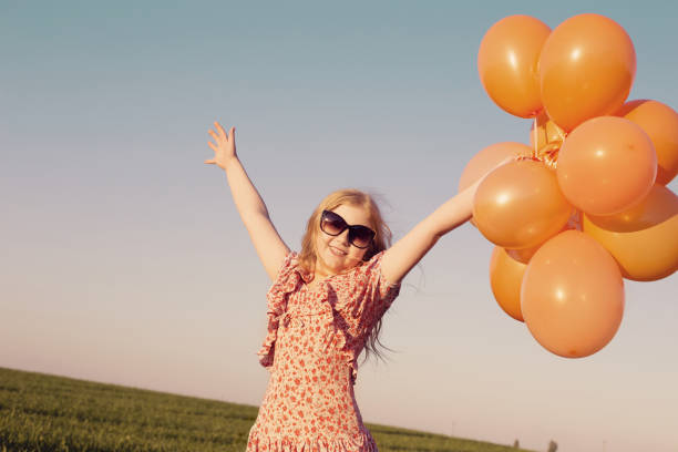 Beautiful little girl playing with air balloons on a windy day