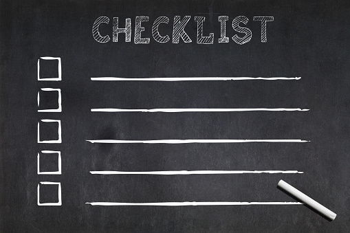 Checklist written on a blackboard with 5 boxes to tick followed by lines and a chalk.