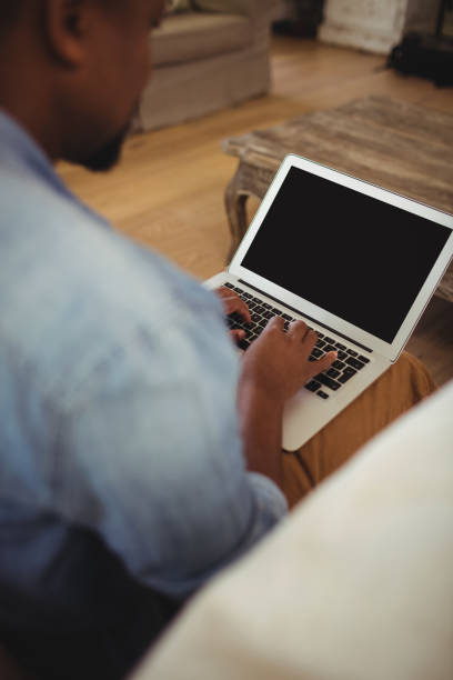 istock Man sitting and using laptop in living room 645971850