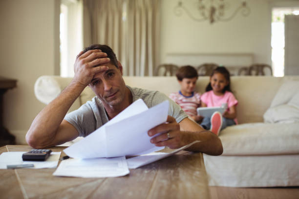 istock Tense man with hand on forehead sitting in living room 645984212