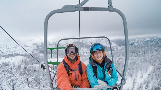 Young man and woman sitting on ski lift.