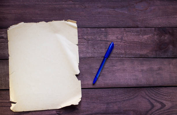 istock Pen with old paper on wooden background 645990506