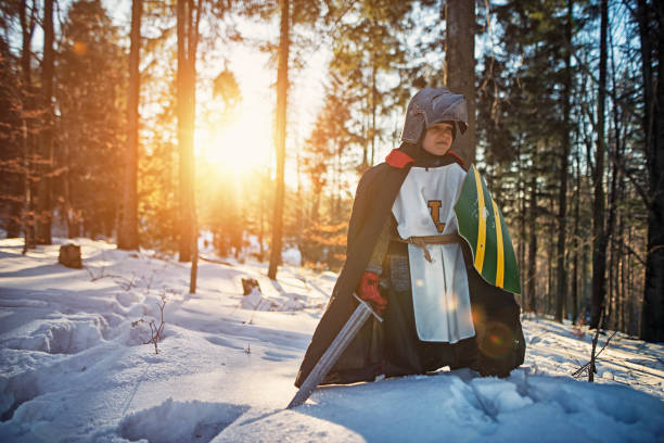 Brave little knight walking in sunny winter forest. The forest is very dangerous but the knight remains corageous and confident. He is concentracing on his quest.\n