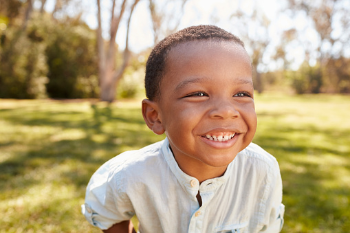 Outdoor Head And Shoulders Shot Of Young Boy In Park