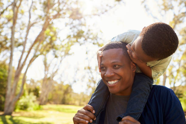 istock Father Carrying Son On Shoulders As They Walk In Park 646011724