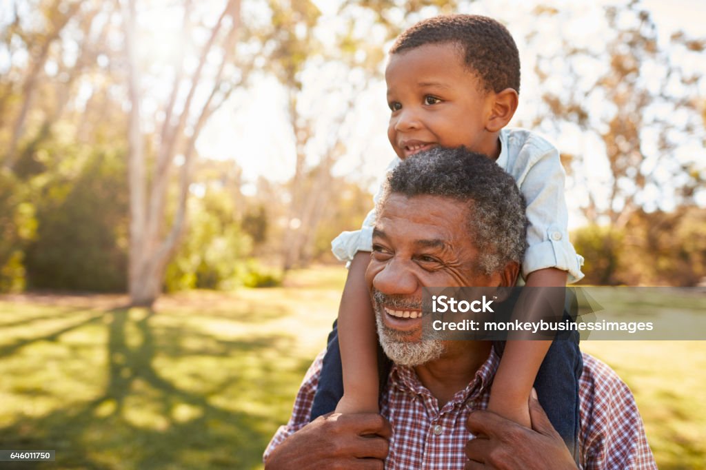 Grandfather Carries Grandson On Shoulders During Walk In Park Grandparent Stock Photo