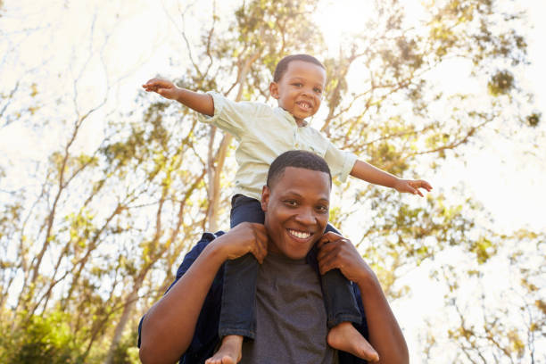 istock Father Carrying Son On Shoulders As They Walk In Park 646011762