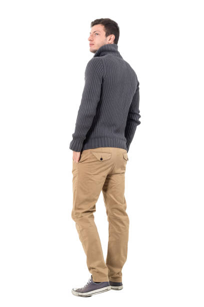Rear view of man in sweater looking up over shoulder Rear view of young casual man in gray sweater looking up over shoulder. Full body length portrait isolated over white background. looking over shoulder stock pictures, royalty-free photos & images