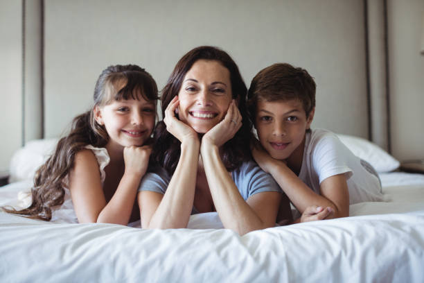 istock Mother and kids lying on bed in bedroom 646017534