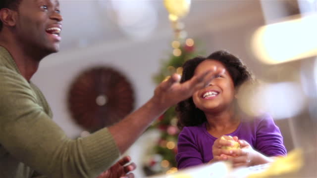 Young girl watches and laughs as father tosses cookie dough into the air