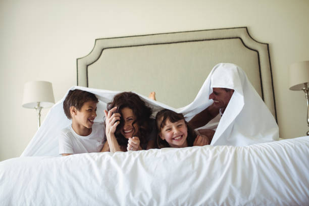 istock Happy family lying under blanket on bed at home 646022892