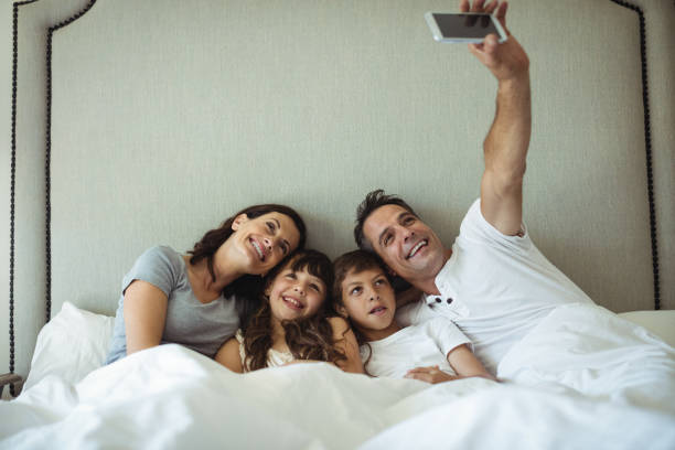 istock Parents and kids taking a selfie on bed 646026004