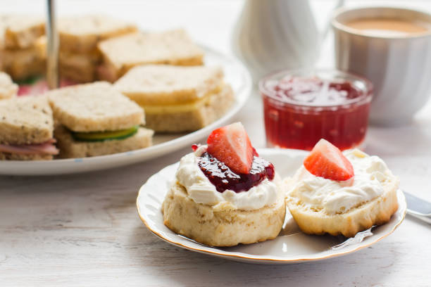 Traditional English afternoon tea: scones with clotted cream Traditional English afternoon tea: scones with clotted cream and jam, strawberries, with various sadwiches on the background, selective focus afternoon tea photos stock pictures, royalty-free photos & images