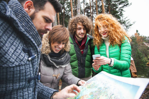 istock Group of friend into wood watching map 646044446