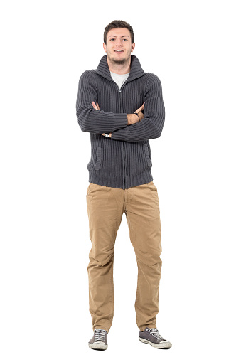Happy man with crossed arms wearing gray zip sweater and ochre pants. Full body length portrait isolated over white background.