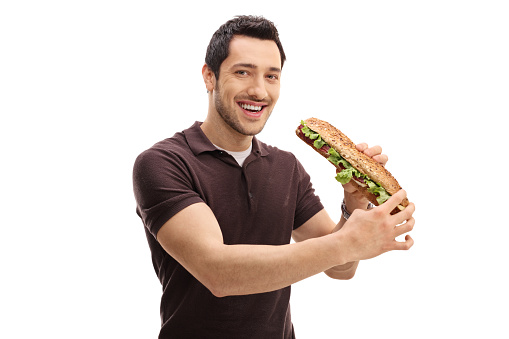 Young man having a sandwich and looking at the camera isolated on white background