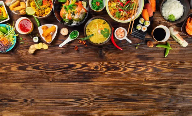 Asian food served on old wooden table, top view, space for text. Chinese and vietnamese cuisine set.