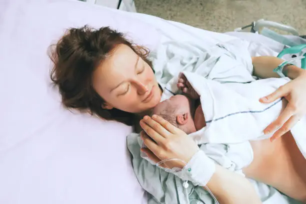 Photo of Mother holding her newborn baby child after labor in a hospital.