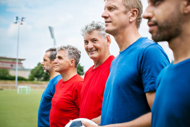 Senior soccer players in a row on the football ground Caucasian man with friends in soccer uniform standing in a row on the football ground before the match club soccer photos stock pictures, royalty-free photos & images