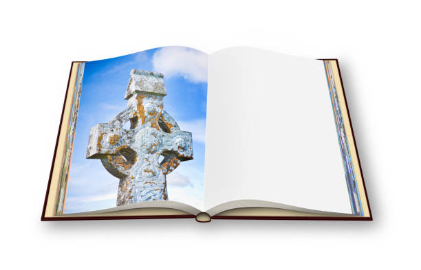 istock Celtic carved stone cross on open photo book. 646108656