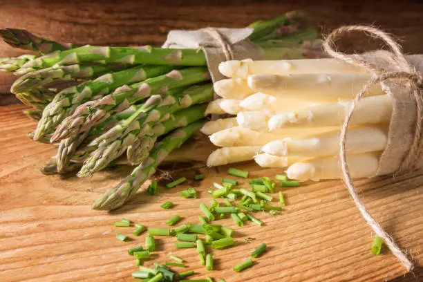 Fresh green and white asparagus with parsley on a wooden table