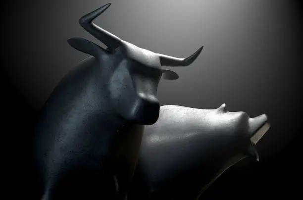 A closeup of two metal castings depicting a stylized bull alongside a bear in dramatic light representing  financial market trends on an isolated dark background - 3D render