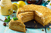 Sweet home layered honey cake on a wooden table with raisins and nuts.