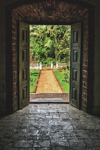 Open doors to the tropical garden, the paved road to the door of the old Indian Villa.Vintage stone floor and walls.