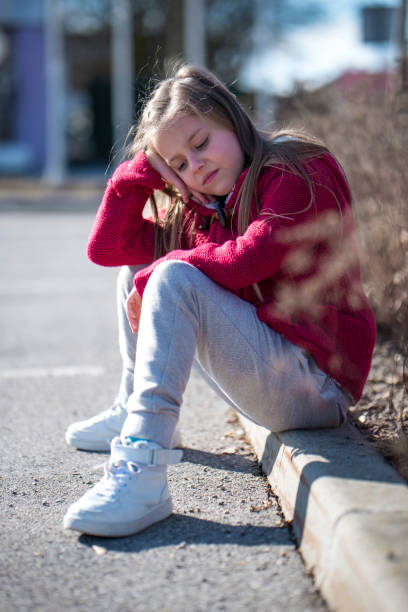 istock Little sad girl sitting on a pavement 646136434