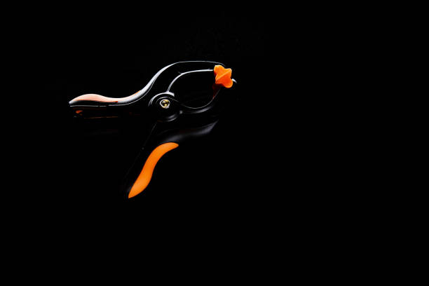 clamp (clip), black plastic, orange ends, on black background