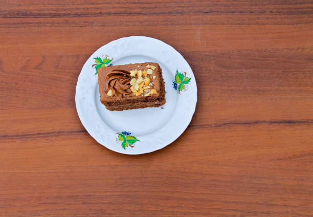 istock Piece of cake with nuts on plate on wooden table. Top view 646144228