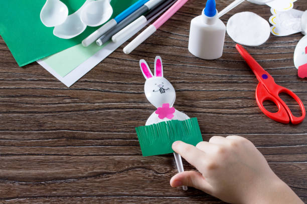 istock The child sticks gift items. Children's Easter gift toy Rooster and the Easter Bunny. Made by hand. Children's Art Project, needlework, crafts for children. 646154796