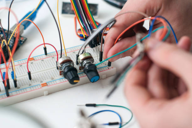 руки, соединяющие провода с доске крупным планом - breadboard стоковые фото и изображения