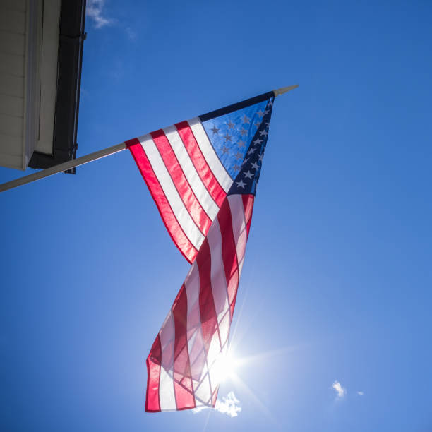istock American flag on blue sky with sun 646168290
