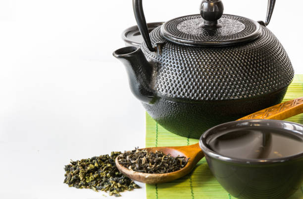 tè verde asiatico impostato su tappetino di bambù con tè verde essiccato in cucchiaio con spazio di copia. concetto di tè asiatico. - chinese tea teapot isolated tea foto e immagini stock